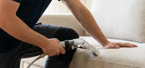 Professional upholstery cleaner deep-cleaning a fabric sofa with a handheld extraction tool, Green Bay, WI.